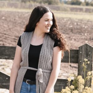 Vrouw in een lang gehaakt grijs vest, buiten in een veld
