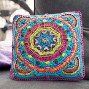 Vierkant gehaakt kussen met kleurrijk mandalapatroon in turquoise, roze en geel